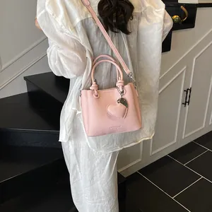 Sac seau rose à motif litchi avec poignées nouées et pendentif en forme de cœur
