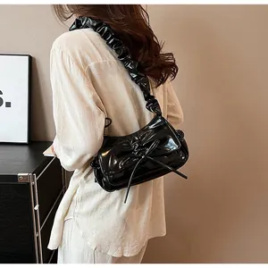 Detailansicht der glänzenden schwarzen Schultertasche mit Falten und Schleifen am Model