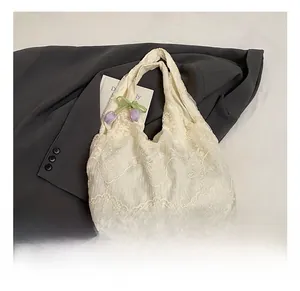Detailed close-up of white lace tote bag with floral embroidery and purple tulip decor