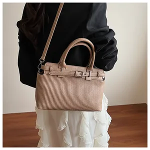 Fashionable khaki pleated texture handbag shown on model with shoulder strap detail