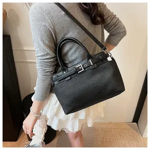 Detail of black leather handbag with vertical quilted stripes and silver metal buckle
