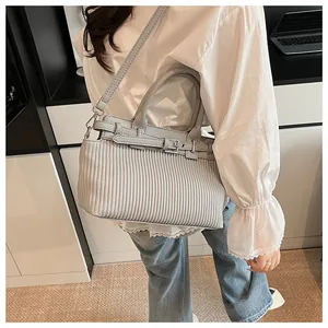 Detail of light gray pleated texture handbag with leather handle and stylish metal buckles