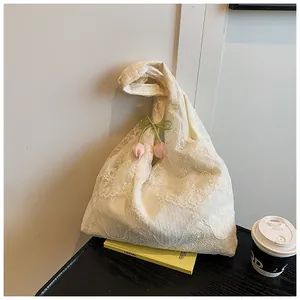 Detailed close-up of beige floral lace tote bag featuring pink tulip pendants and a green bow