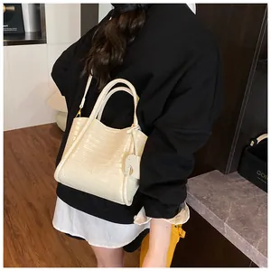 Sac seau chic crème motif crocodile avec bandoulière réglable porté par un mannequin