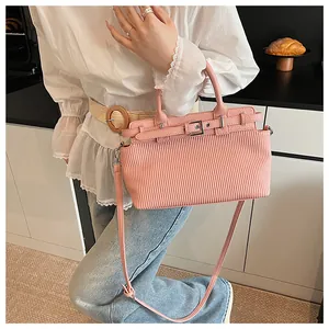 Close-up of pink pleated handbag with silver buckle detail on a white blouse background