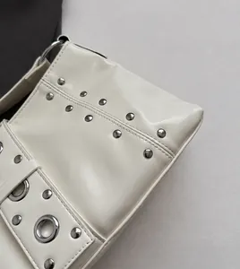 Dettaglio borsa tote in pelle bianco crema con borchie argentate e occhielli in metallo