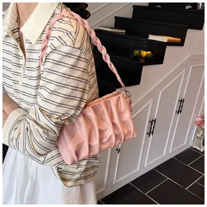 Detail of light pink ruched cloud bag with woven strap on striped shirt outfit