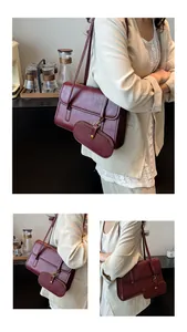 Detail van vintage bordeauxrode lederen schoudertas met bijpassende mini-bedel en flap