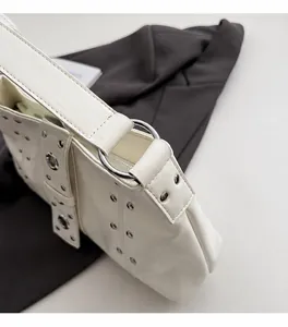 Dettaglio della borsa tote in pelle color panna con occhielli argento e borchie metalliche