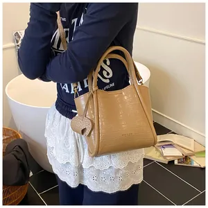 Détail du sac seau kaki à motif crocodile avec breloque éléphant dans un décor de vie
