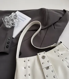 Dettaglio della borsa a spalla in pelle bianca con rivetti argento e grandi occhielli in metallo
