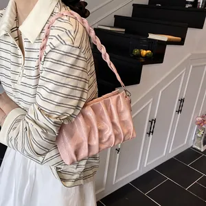 Light pink ruched cloud bag with woven strap shown on model in a minimalist setting