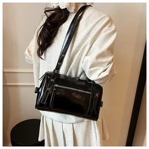Detail of black glossy patent leather pillow bag with metal zipper and eyelet strap