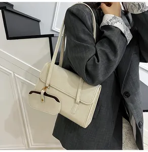 Detail van de crème onderarmtas met bijpassende munttas op een grijze geruite blazer