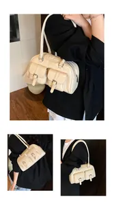 Detail of cream bowling bag showing dual front flap pockets and metallic buckle accents