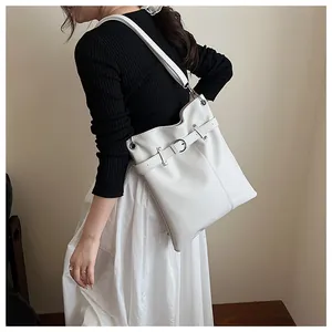 Detail of white pleated tote bag with decorative belt buckle shown on shoulder