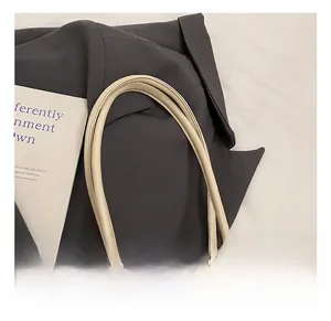 Detailed macro view of the cream-colored bowling bag's rounded leather handles and silver ring