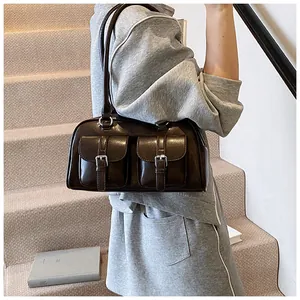 Detail of dark brown glossy shoulder bag with silver buckles in a lifestyle setting