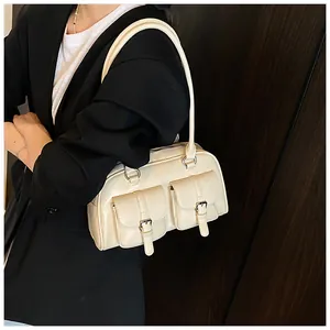 Detail of a creamy white bowling bag with dual front buckle pockets and glossy finish