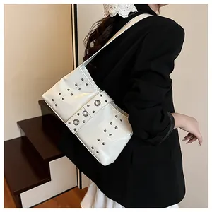 Borsa a spalla minimalista in pelle verniciata bianca con rivetti argentati indossata dal modello