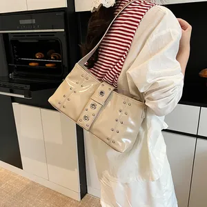 Borsa hobo chic in vernice beige con borchie metalliche e tracolla con grandi occhielli