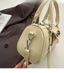Detail of cream pillow bag showing silver rivets, metal hardware, and side pocket detail