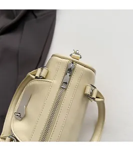 Detailed shot of smooth silver zipper and metal buckle on cream faux leather handbag