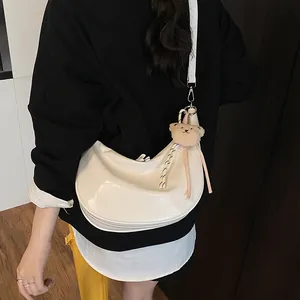 White croc-textured crescent bag with cute bear charm worn by a model in a casual setting