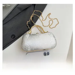 Detailed view of snakeskin pattern evening clutch with gold handle and smartphone for size