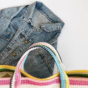 Detail der mehrfarbigen Raffia-Tasche mit dicken Griffen und gestreifter Webstruktur