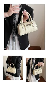 Detail view of cream Boston bag showing the heart pendant and metallic stud accents