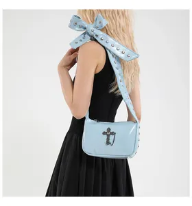 Detail of light blue crossbody bag with studded bow shoulder strap and silver cross pendant