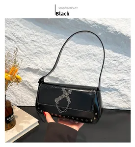 Detail of gothic black glossy leather bag featuring metallic cross and rivet studs