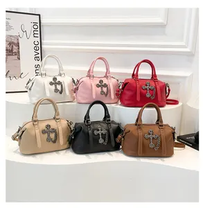 Detalle de colgante de cruz y cadenas plateadas en bolsos de cuero coloridos