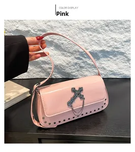 Detail of pink crossbody bag with vintage metal cross, silver chains and rivets decoration