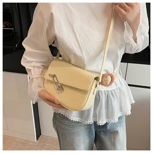 Detail der beige Umhängetasche mit silberner Nadelschnalle am Model in moderner Küche