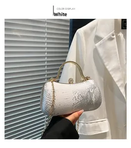 Detail of white snakeskin texture evening bag with gold handle and crystal clasp