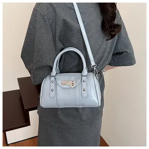 Close-up of light blue pillow bag with heart metal lock and silver rivet accents