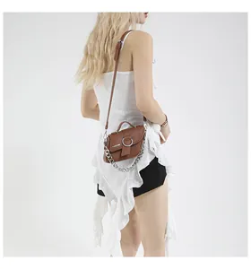 Détail d'un sac besace en cuir marron avec chaîne argentée et boucle à anneau métal