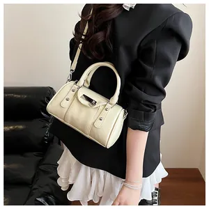 Close-up of cream leather pillow bag featuring silver rivet details and magnetic buckle