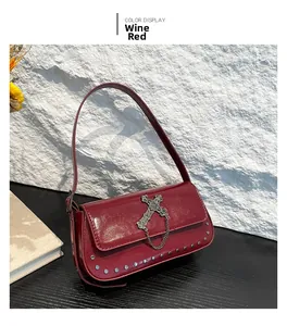 Detail view of wine red baguette bag with metal cross, decorative chain and silver rivets