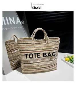 Détail du sac cabas en paille rayé kaki avec broderie noire et poignée dans un décor élégant