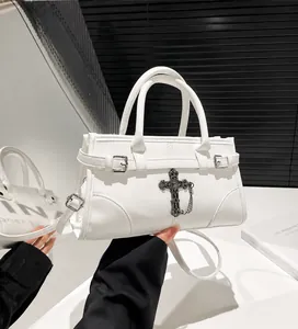 Detail of white leather tote featuring a gothic metal cross and detachable shoulder strap