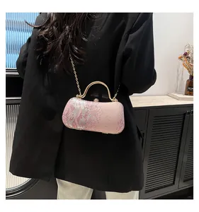 Pink shimmering snakeskin textured evening clutch bag with gold chain strap shown on model