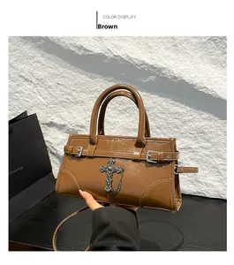 Detail of glossy brown handbag with silver cross pendant and dual handles for hand carry
