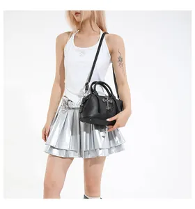 Detalle del bolso tote negro con cruz decorativa, textura de piel y adornos metálicos