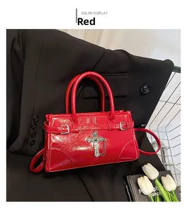 Detail of red patent leather handbag with metal cross pendant and strap on black blazer