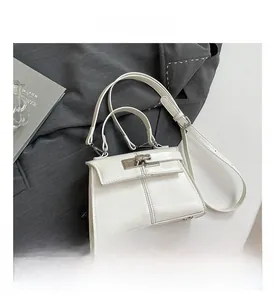 Detailed view of white leather handbag with elegant metal lock and sturdy handle strap