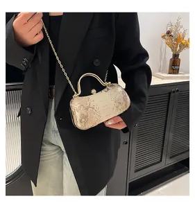 Detail of gold snakeskin evening bag with rhinestone clasp and metal chain strap