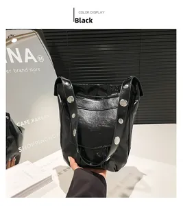 Gros plan du sac seau noir verni avec de larges clous argentés sur la bandoulière